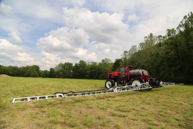 Self-propelled crop sprayer with booms extended across a field